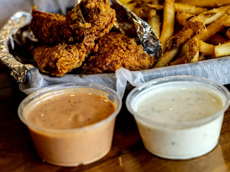 Two house-made Wing Doozy dips in ramekins with wings and fries behind